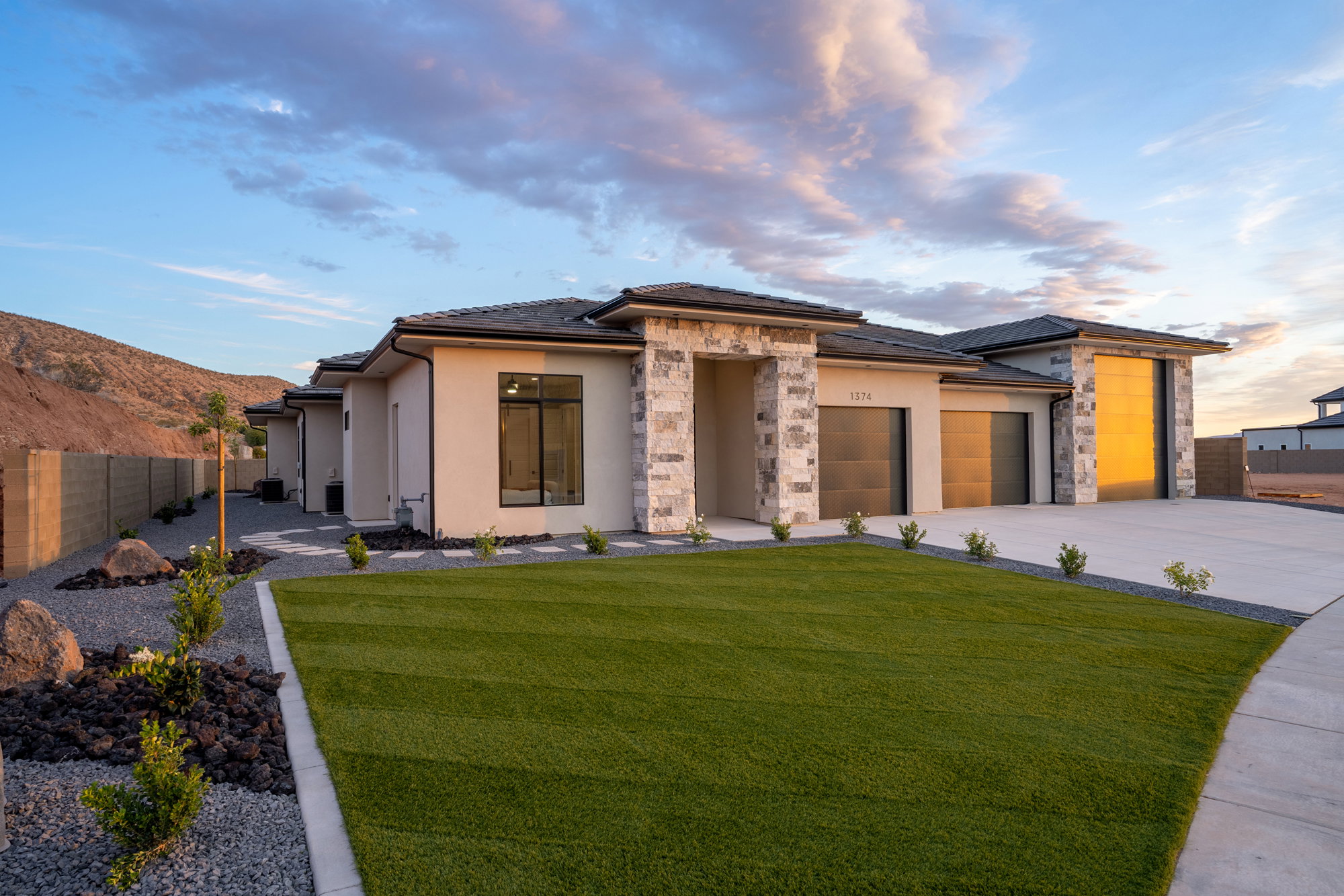 Contemporary stucco exterior with stone accents, featuring a multi-car garage