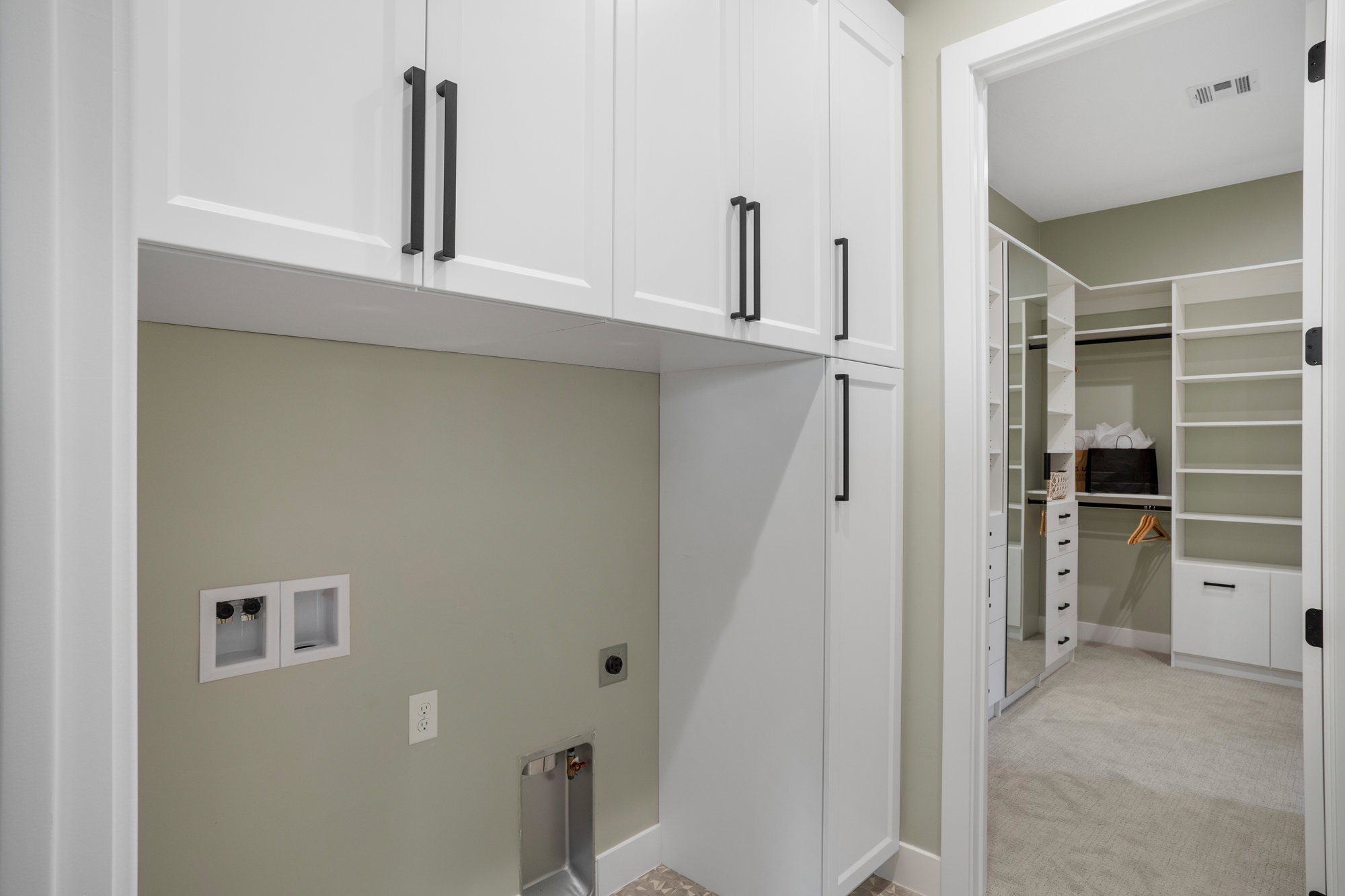 Laundry area featuring white cabinetry with matte black hardware