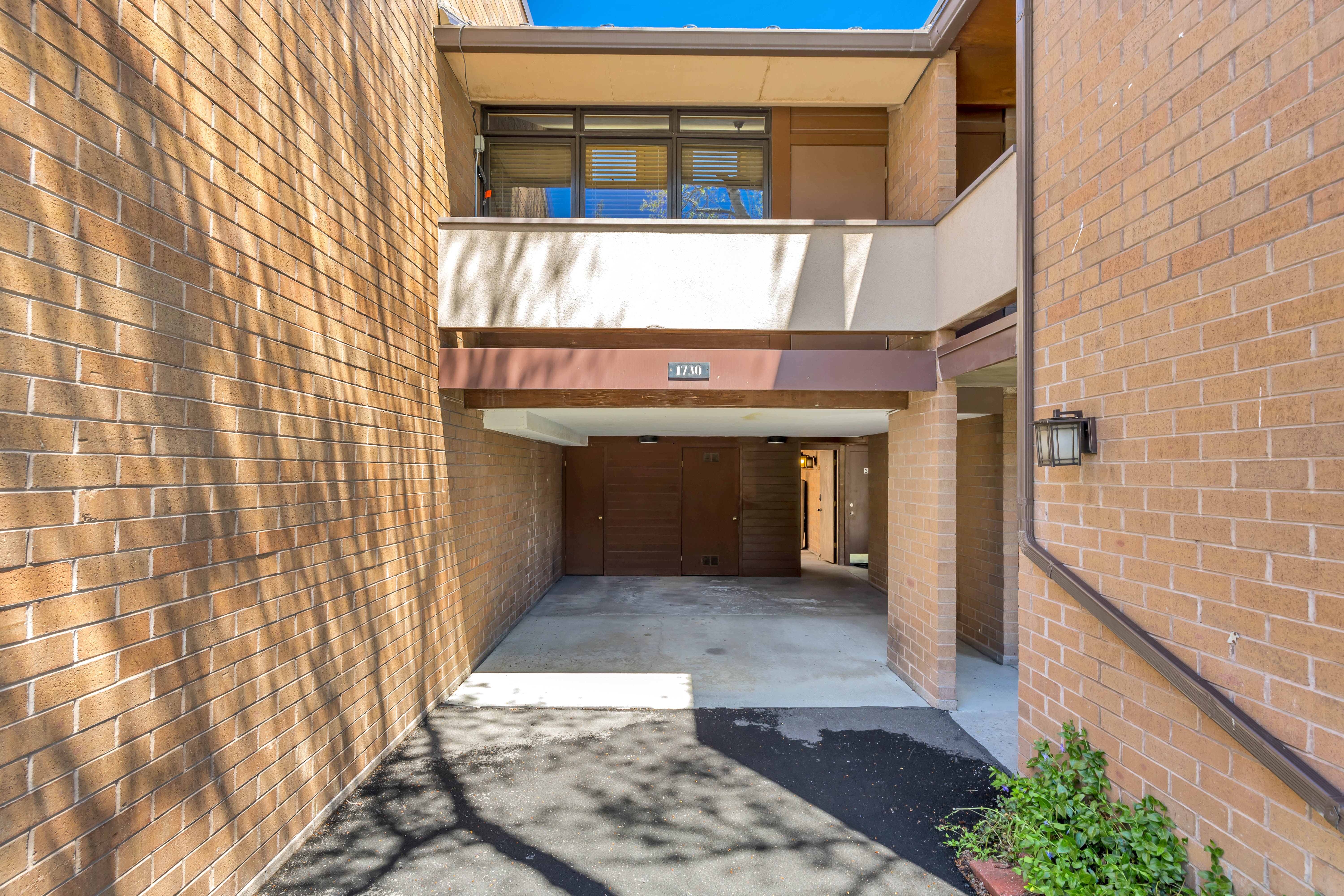View of unit with carport and the balcony off of the primary bedroom