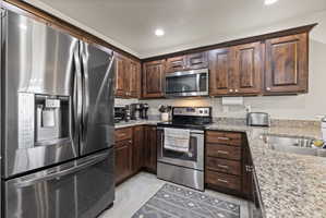 Spacious open concept kitchen featuring dark wood cabinetry, granite countertops, stainless steel appliances, and a walk-in pantry