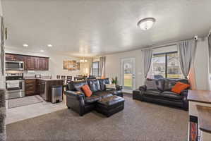 Open-concept living space featuring both carpet and tile flooring, light colored paint, and natural lighting