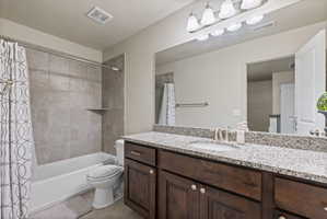 Spacious full bathroom featuring tub shower combo with tile surround, tile flooring, dark wood cabinetry and granite countertops