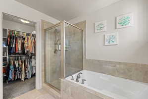 Primary bathroom featuring separate soaker tub and shower with tile surrounds, tile flooring, dual sink vanity with dark wood cabinetry and granite countertops