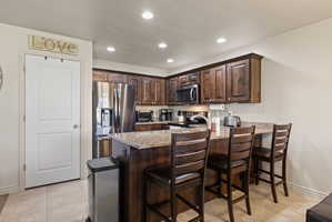 Spacious open concept kitchen featuring dark wood cabinetry, granite countertops, stainless steel appliances, and a walk-in pantry