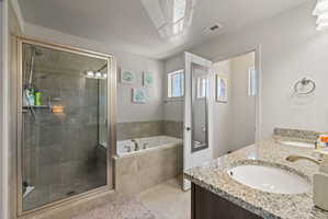Primary bathroom featuring separate soaker tub and shower with tile surrounds, tile flooring, dual sink vanity with dark wood cabinetry and granite countertops