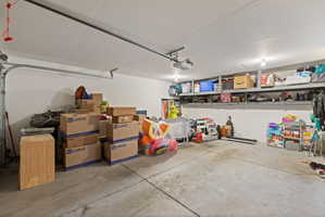 Spacious garage featuring concrete flooring and overhead storage shelving