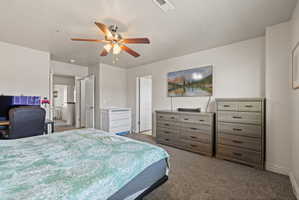 Spacious primary bedroom featuring carpet flooring, light neutral paint, large window and ceiling fan