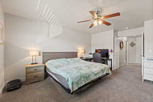 Spacious primary bedroom featuring carpet flooring, light neutral paint, large window and ceiling fan