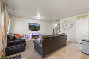 Open concept living area featuring light neutral paint, carpet and tile flooring, and natural light