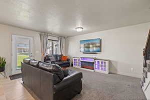 Spacious living area featuring carpet flooring, large window, and entry to back patio