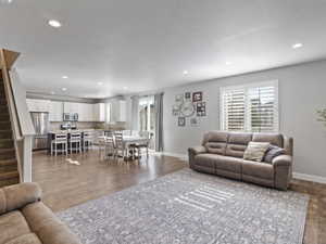 Open-concept living area featuring wood-finish flooring, recessed lighting, and a window with plantation shutters