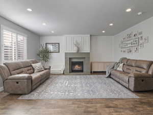 Living area featuring wood-finish flooring, recessed lighting, and a fireplace with a concrete-style hearth and mantle