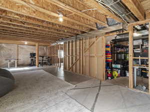 Unfinished basement featuring exposed wood joists, concrete flooring, and framed walls