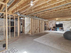 Unfinished basement featuring exposed wood framing, concrete flooring, and visible ductwork