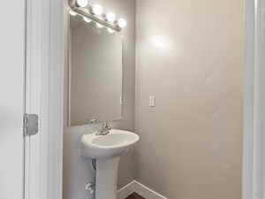 Pedestal sink with a chrome faucet, illuminated by a four-bulb vanity light fixture