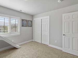 Room featuring neutral-toned carpet flooring, light gray walls, and white trim throughout