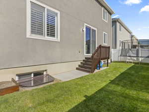 Expansive green lawn with concrete patio, leading to a wooden deck with stairs