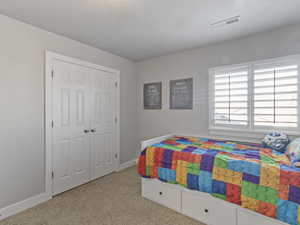 Bedroom featuring twin bi-fold closet doors, wall-mounted window shutters, and plush carpet flooring