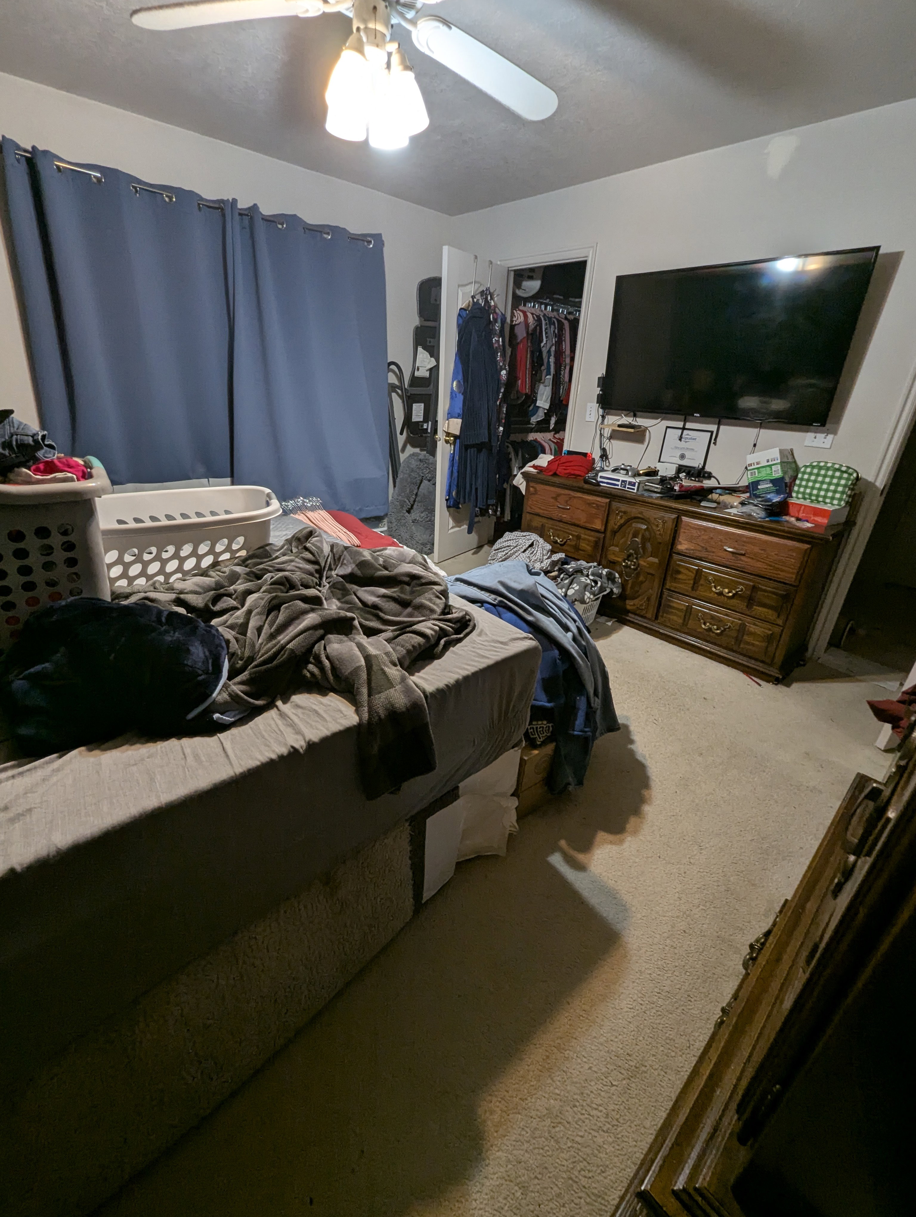 Carpeted room featuring a ceiling fan with integrated lighting, window with curtain rods, and an open closet with interior rod