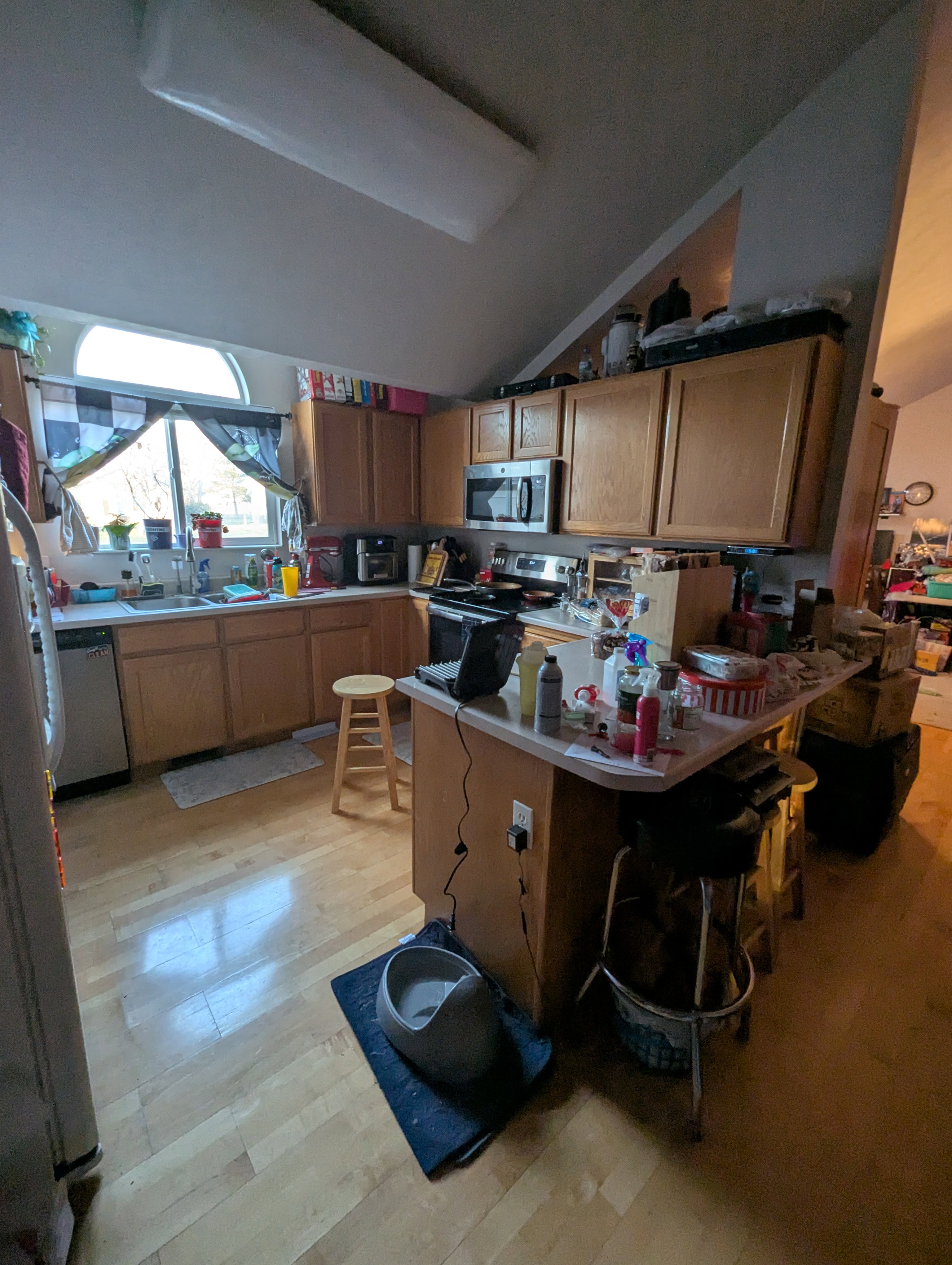 Kitchen featuring wood-finish flooring, ample wood cabinetry, a built-in microwave, and a window above the sink