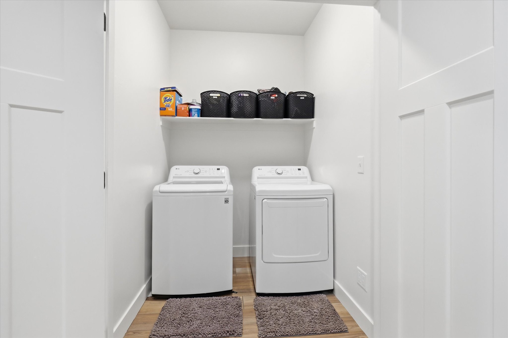 Dedicated laundry area featuring a built-in shelf, wood-finish flooring, and crisp white trim