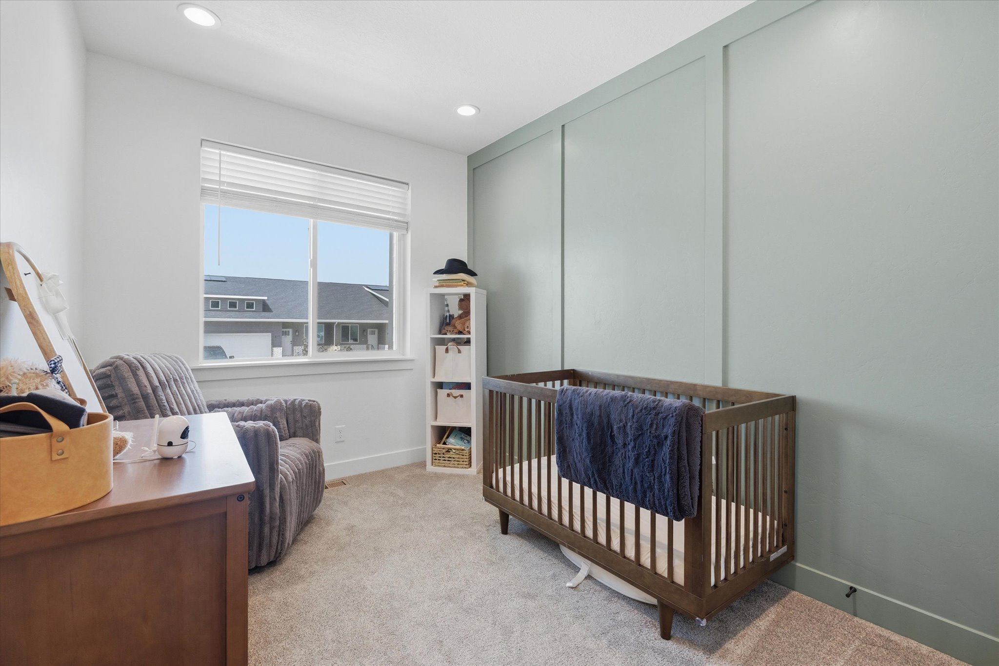 Room featuring a full wall of vertical paneling, recessed lighting, and a large window with horizontal blinds