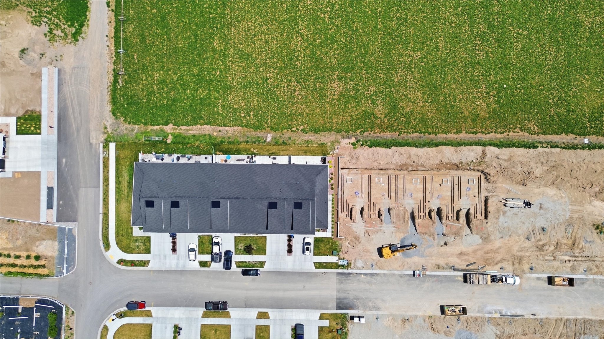 Aerial perspective showcasing a multi-unit residential building with a dark shingled roof and individual parking spaces