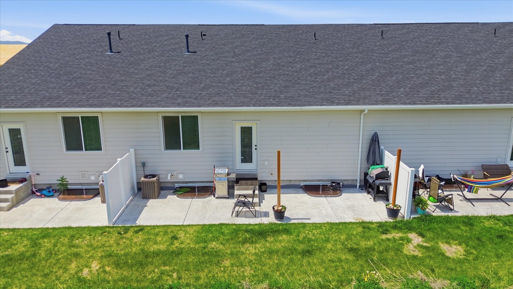 Rear exterior featuring light-colored siding and a dark shingle roof