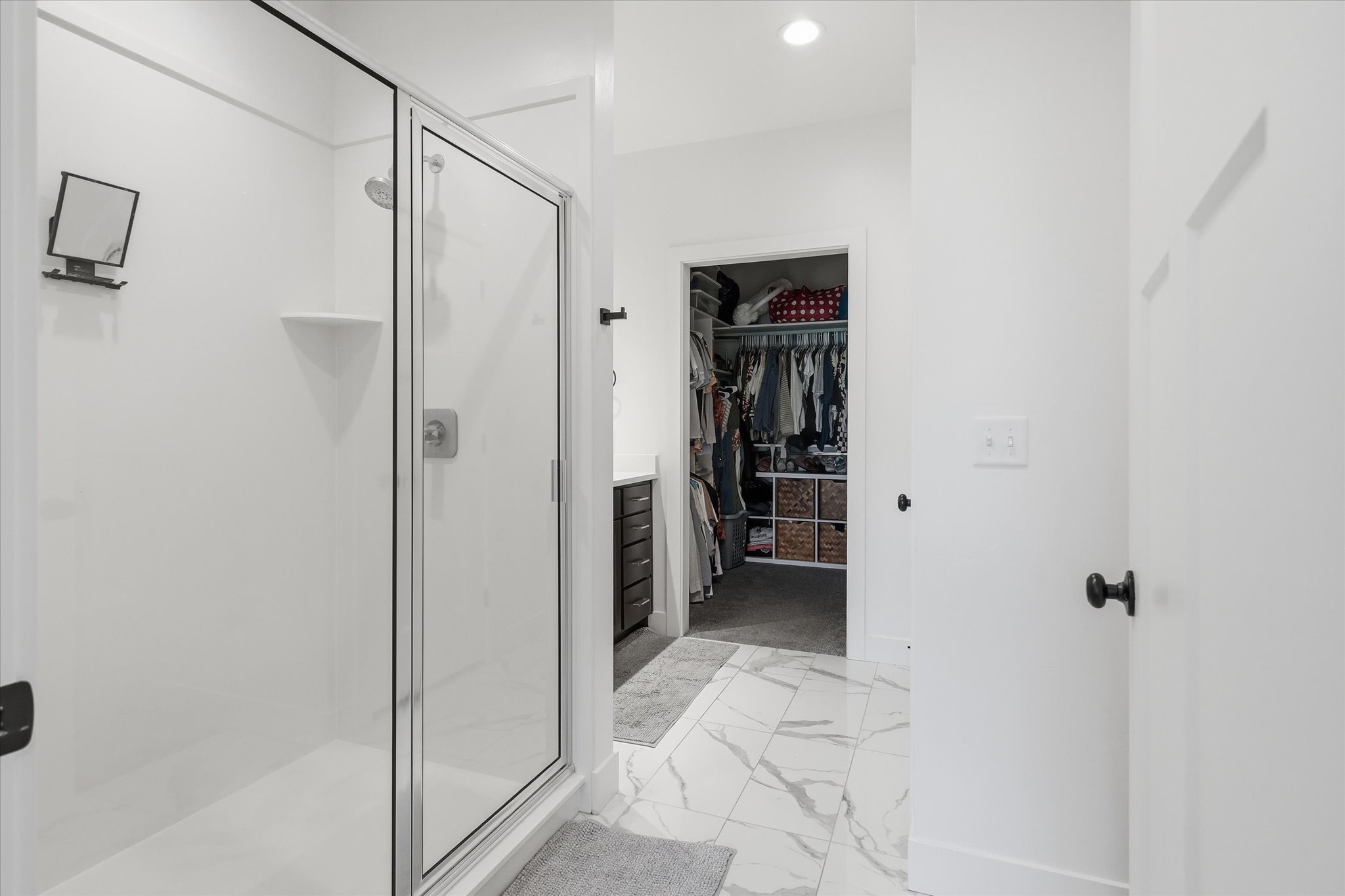 Bathroom featuring a glass-enclosed shower with a built-in shelf, marble-look tile flooring, and recessed lighting