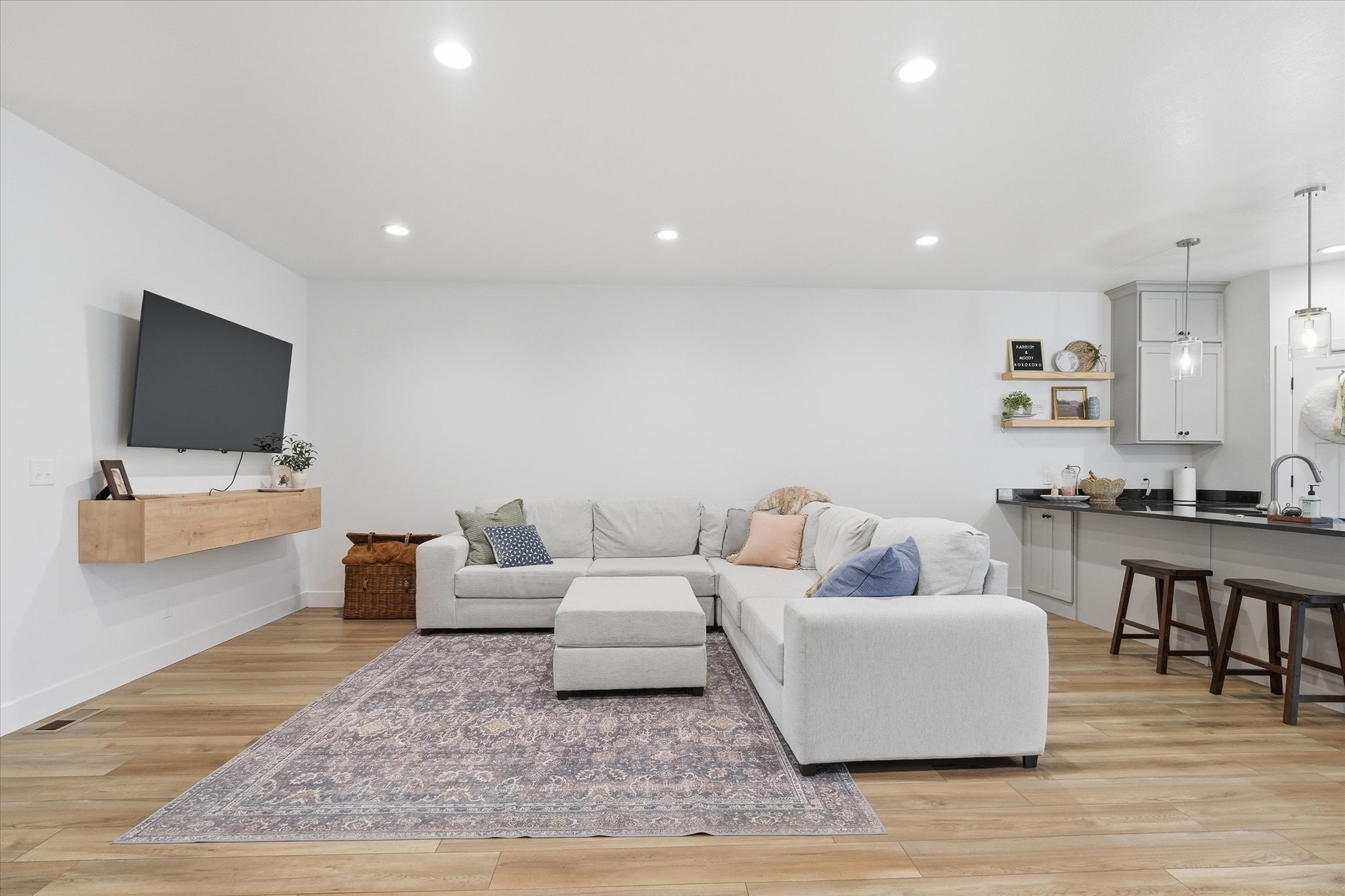 Open-concept living area with wood-finish flooring, recessed lighting, and a floating entertainment console