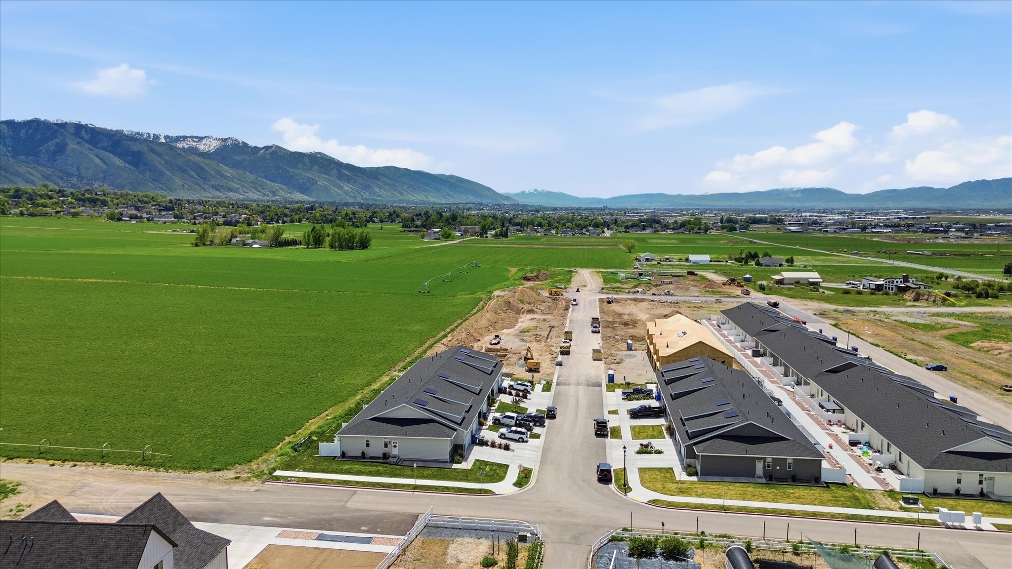New construction community featuring multiple townhome buildings with dark shingle roofs and light-colored siding