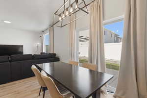 Dining area featuring a contemporary linear chandelier and light wood-finish flooring