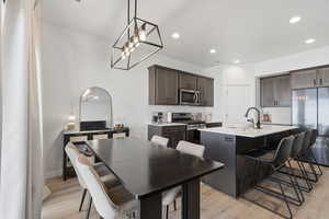 Open-concept kitchen and dining area featuring wood-finish flooring, recessed lighting, and a linear pendant light fixture