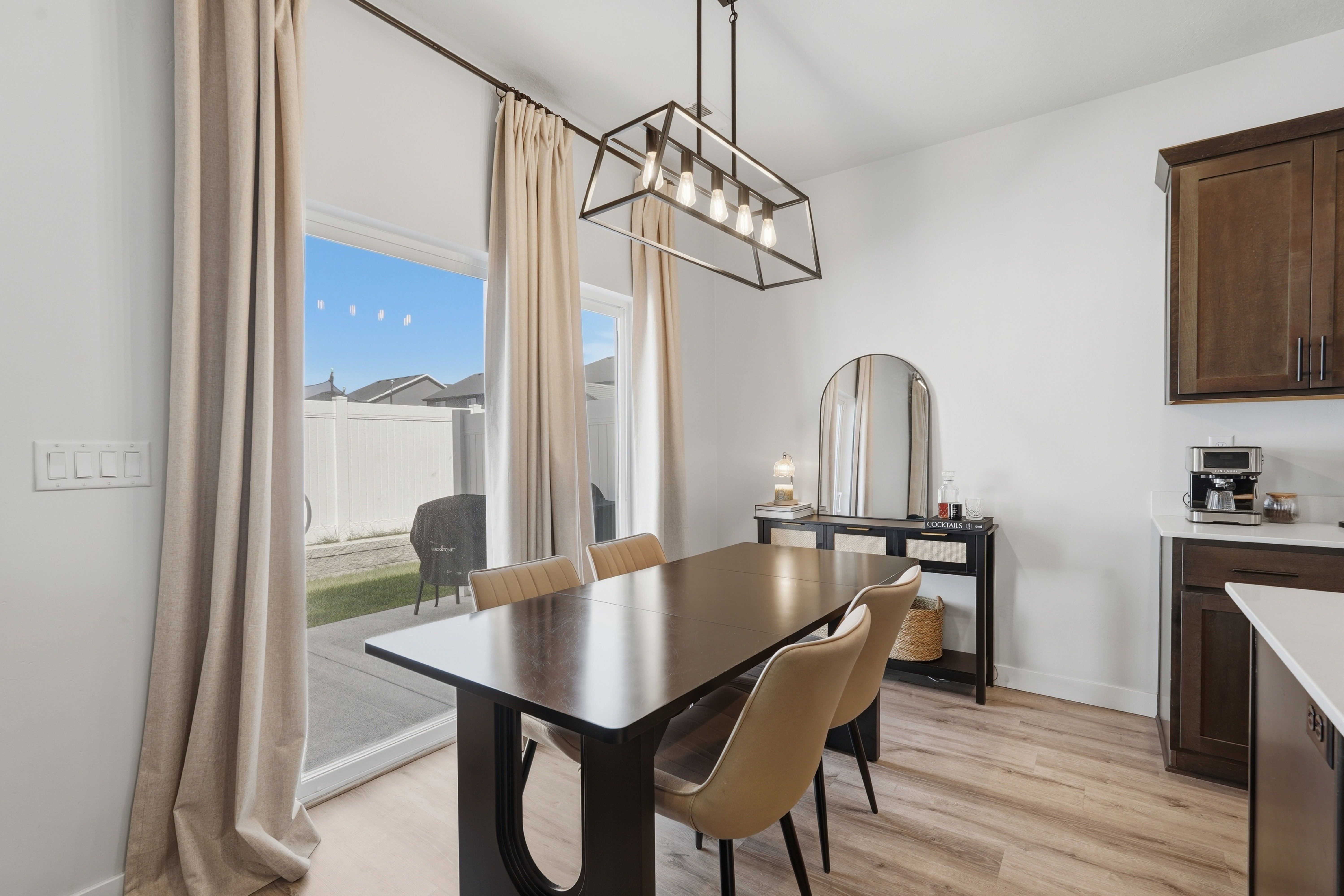 Dining area featuring wood-finish flooring, a contemporary linear chandelier, and sliding glass door access to the backyard patio