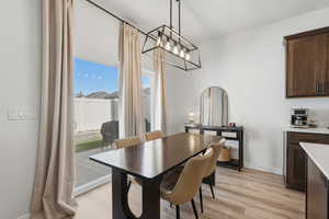 Dining area featuring wood-finish flooring, a contemporary linear chandelier, and sliding glass door access to the backyard patio