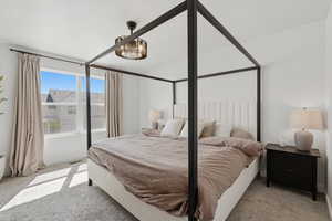 Bright bedroom featuring a large window, soft carpeting, and a ceiling-mounted light fixture