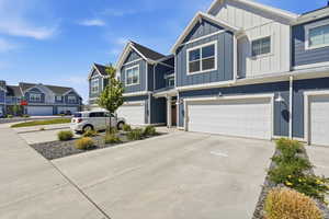 Modern townhome exterior featuring blue vertical siding, white board and batten accents, and white paneled garage doors