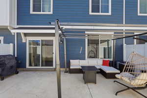 Private concrete patio featuring a modern pergola structure, blue siding, and white trim