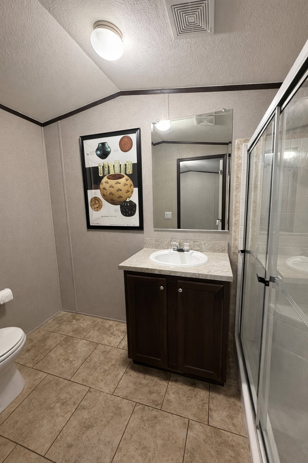 Bathroom featuring a dark wood vanity with a light countertop, a white sink, and a mirrored wall cabinet
