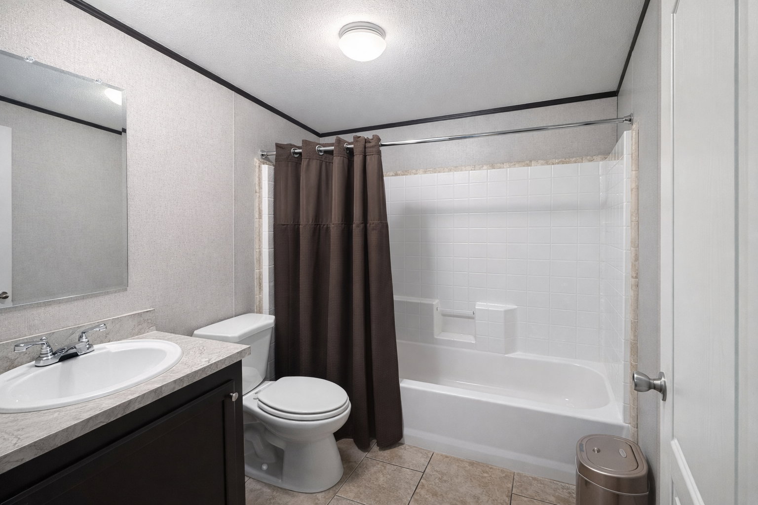 Bathroom featuring a white tub/shower combination with subway tile surround, dark wood-finish vanity with an integrated sink, polished chrome faucet, and a wall-mounted mirror