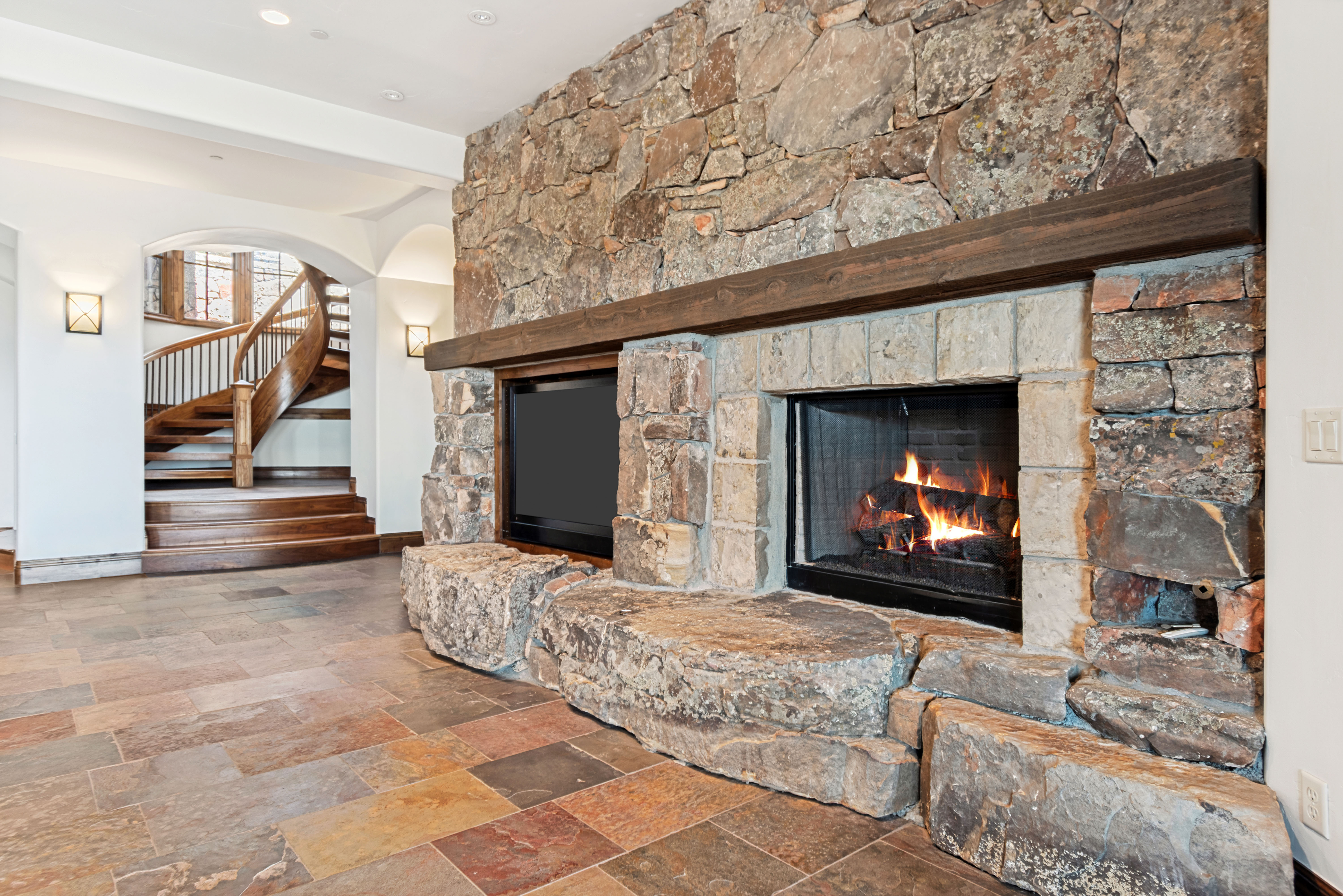 Stone fireplace featuring a timber mantel and integrated media niche