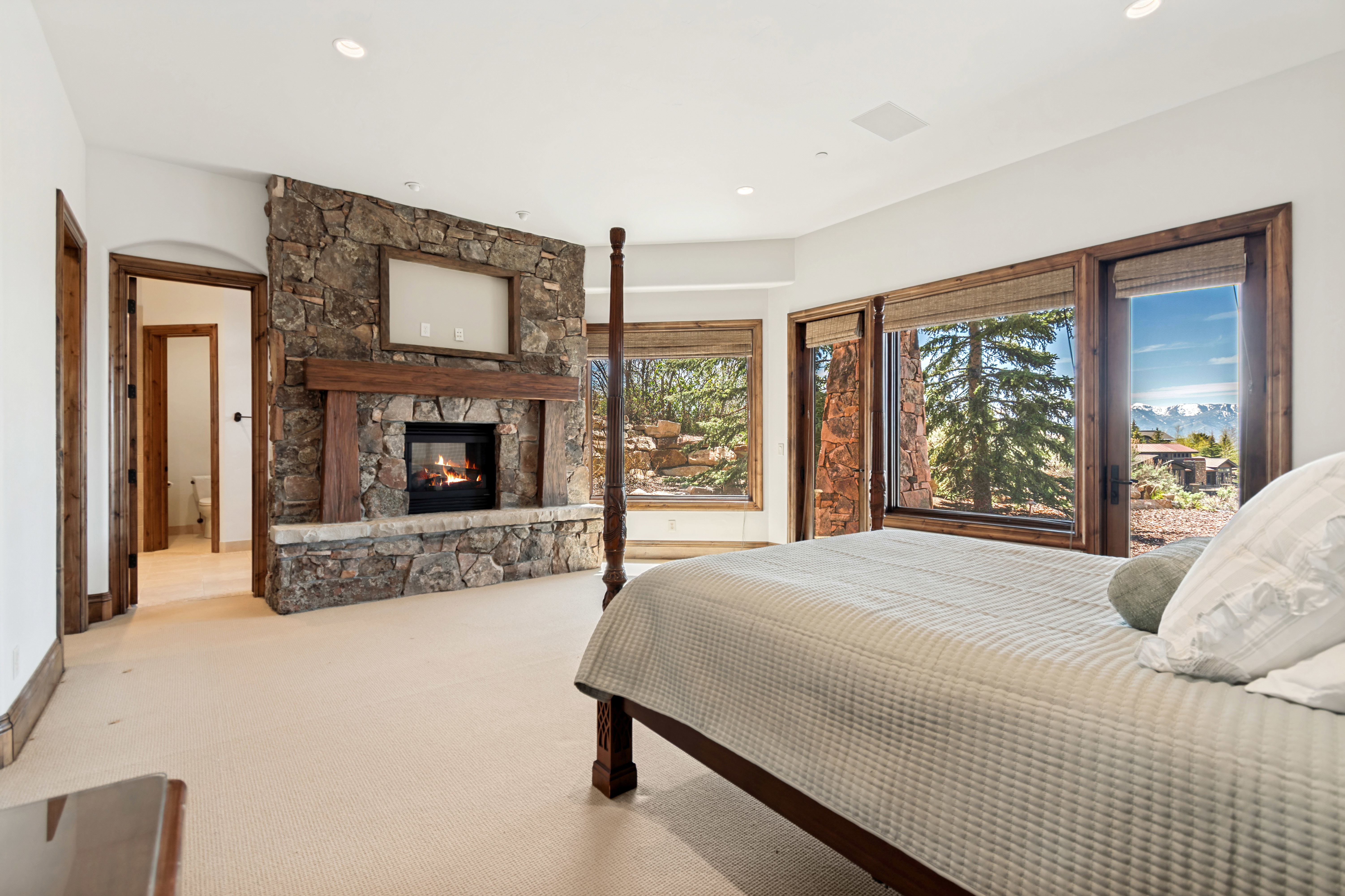 Expansive room featuring a stone fireplace with a wood mantle, multiple windows with wood-finish frames, and recessed lighting