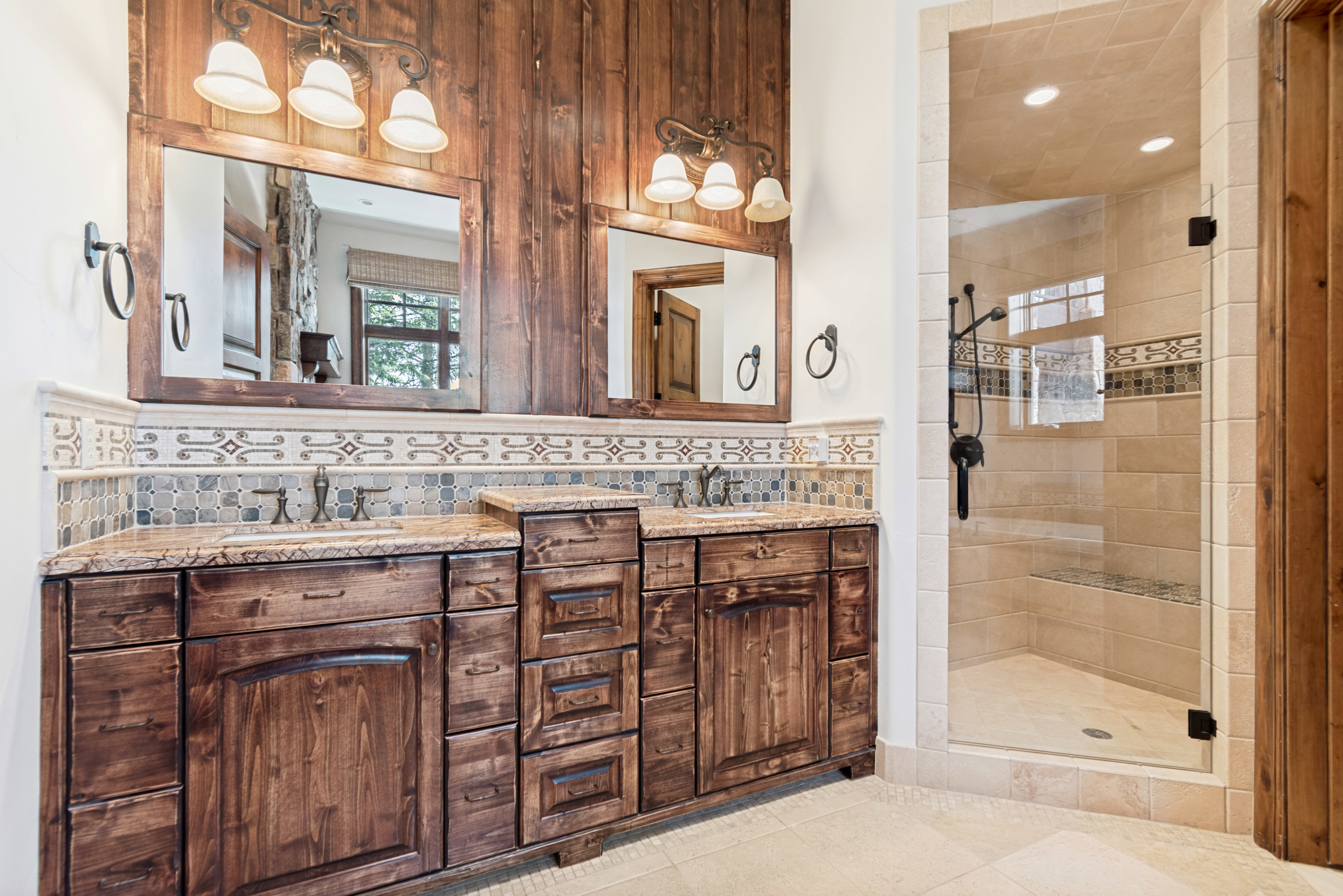 Dual wood vanities with stone countertops and undermount sinks