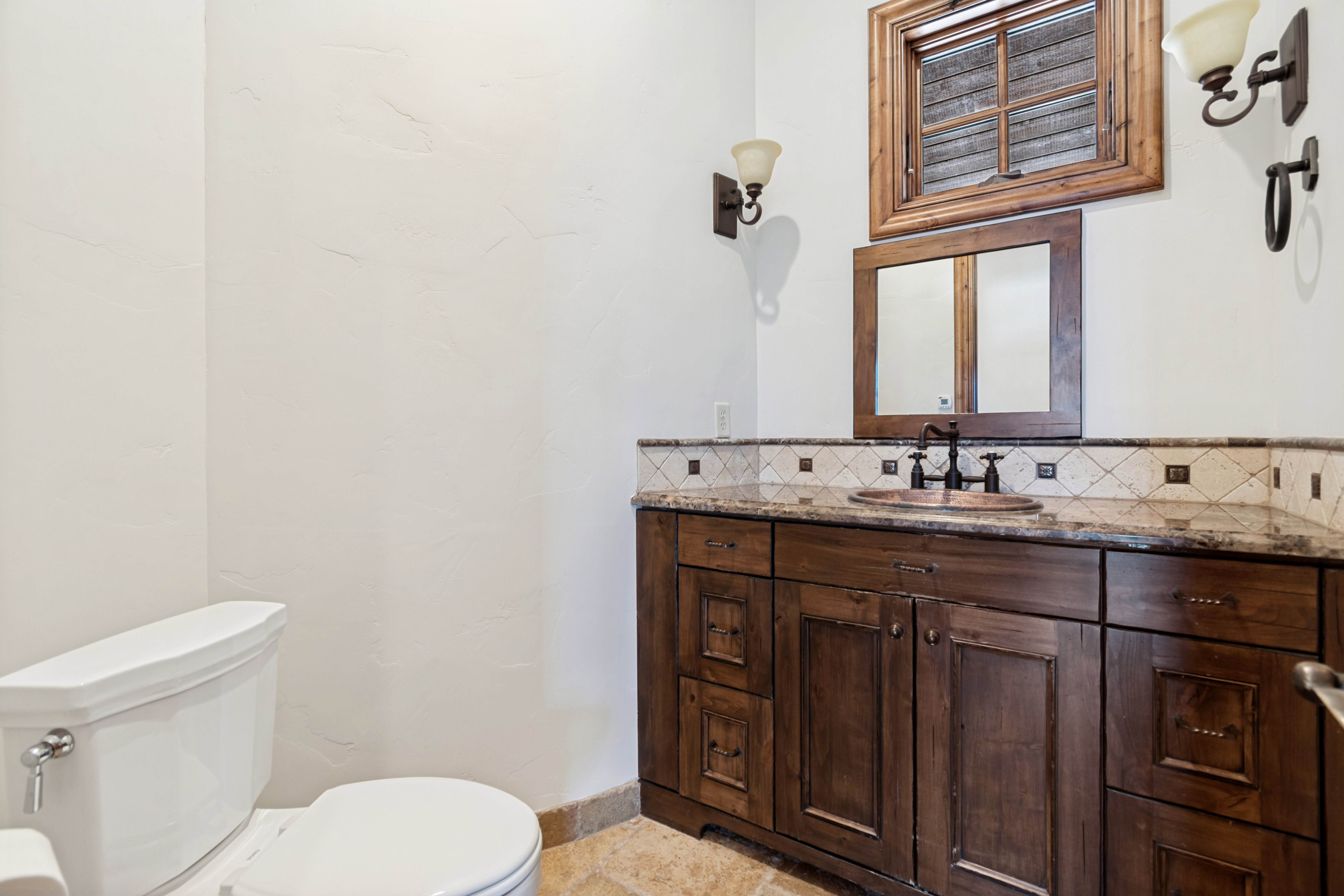 Powder room featuring a custom wood vanity with a stone countertop, an integrated vessel sink with a dark bronze faucet, and a decorative tile backsplash