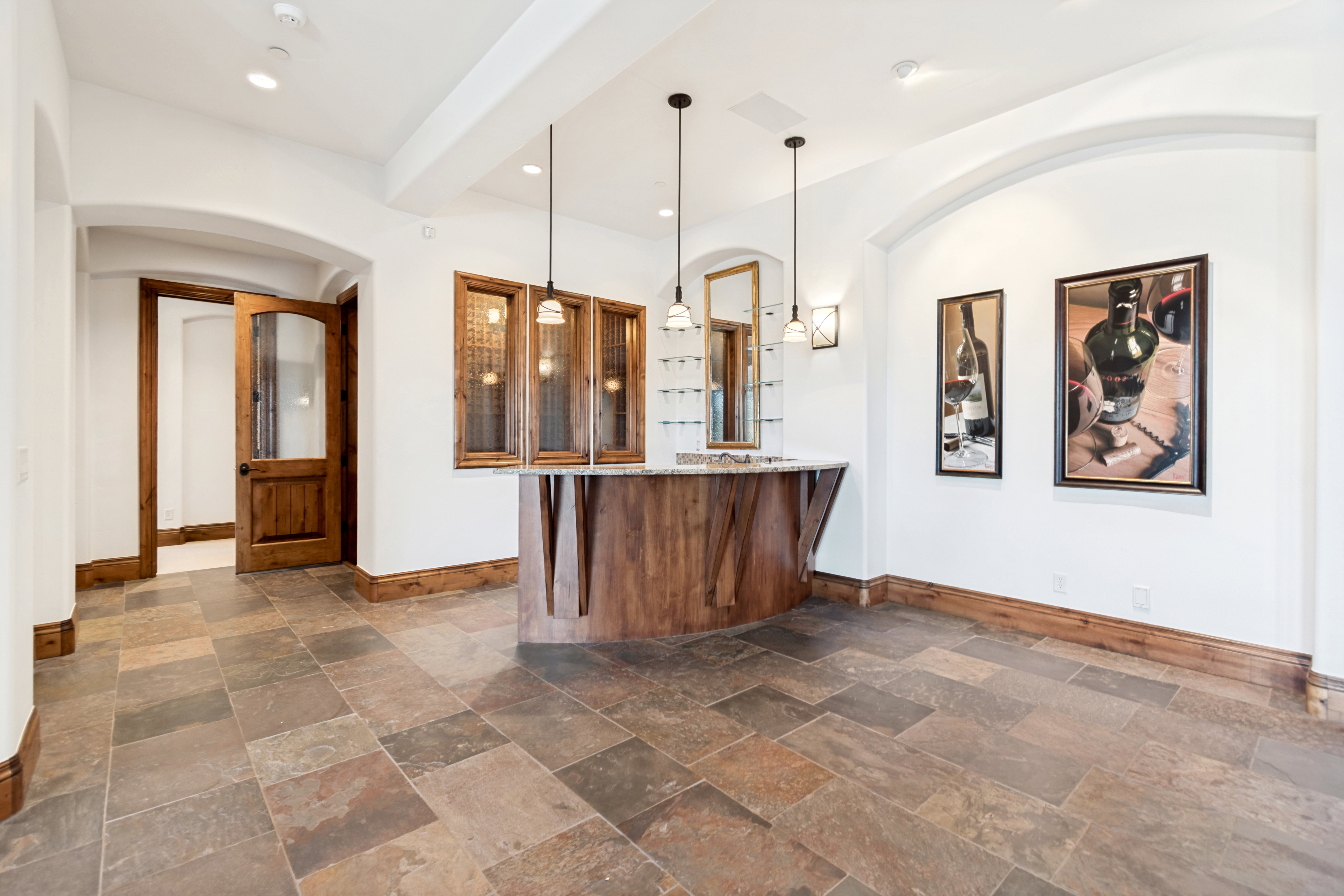 Spacious room featuring multi-toned slate flooring and a custom wood-finish bar with a light-toned countertop