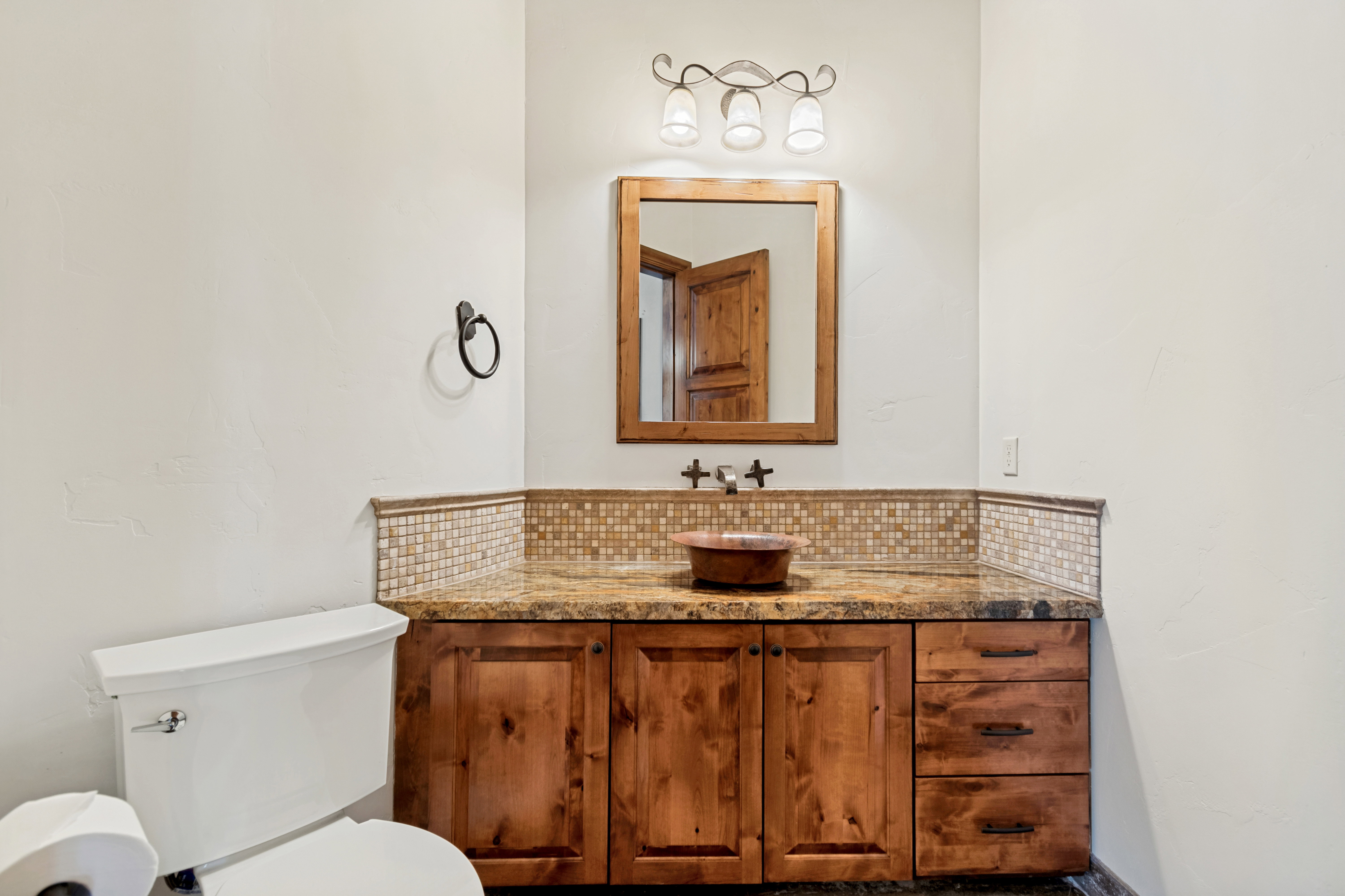 Custom wood vanity with integrated basin, stone countertop, and mosaic tile backsplash