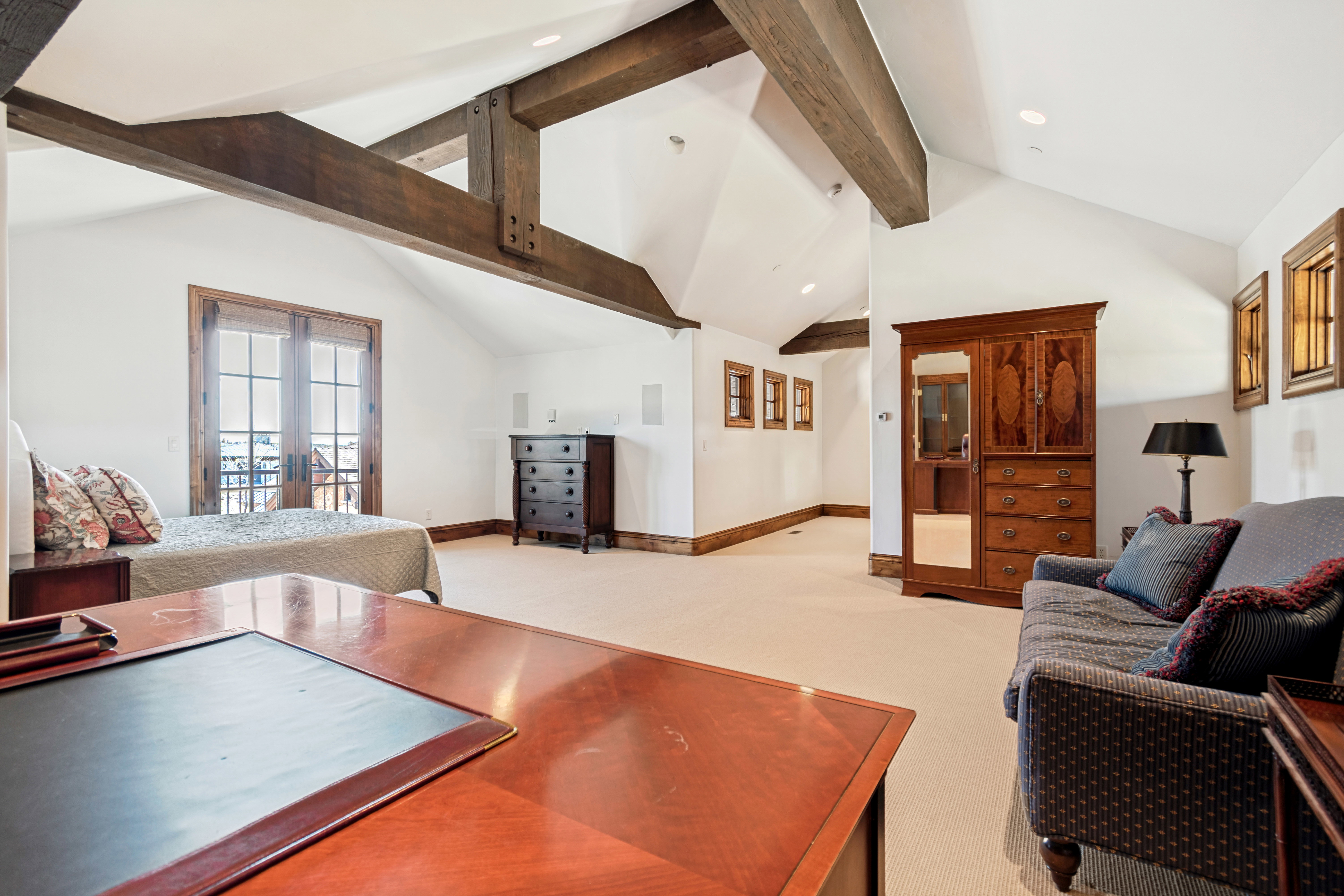 Vaulted ceiling room featuring exposed wood beams and light-colored carpeting