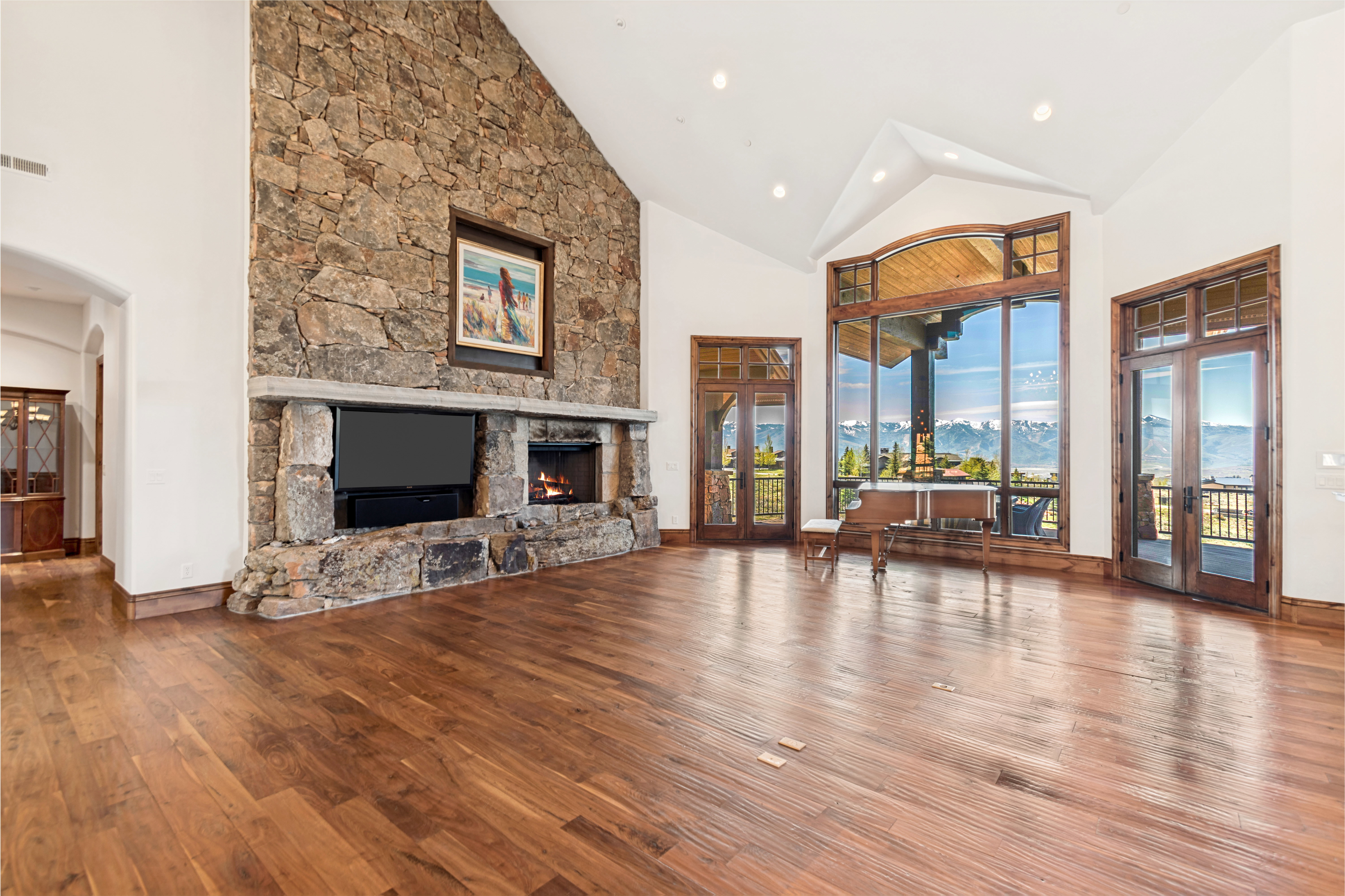 Spacious living area featuring a floor-to-ceiling stone fireplace, recessed media niche, and wood-finish flooring