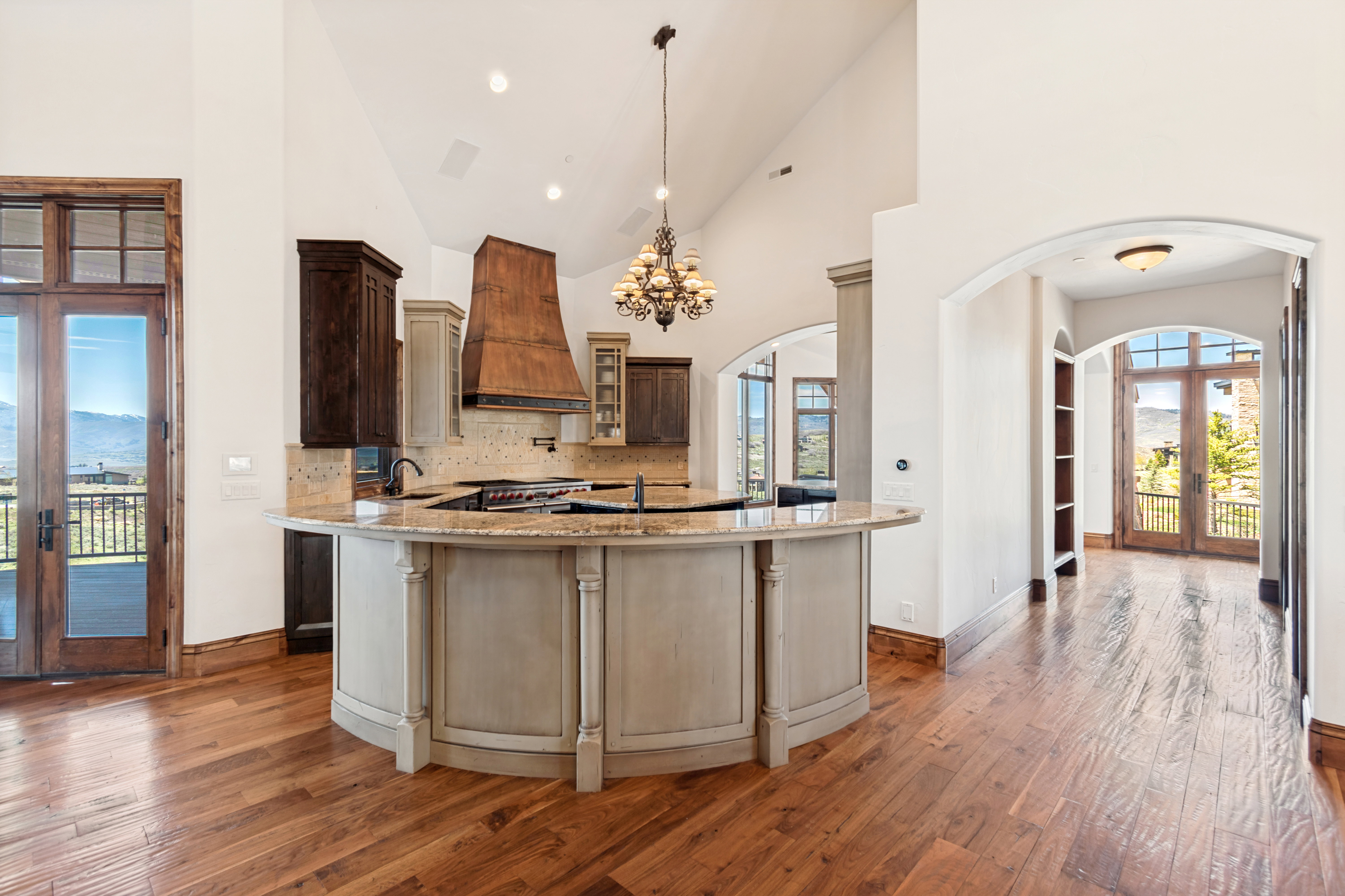 Gourmet kitchen with a large curved island, granite countertops, and a custom range hood