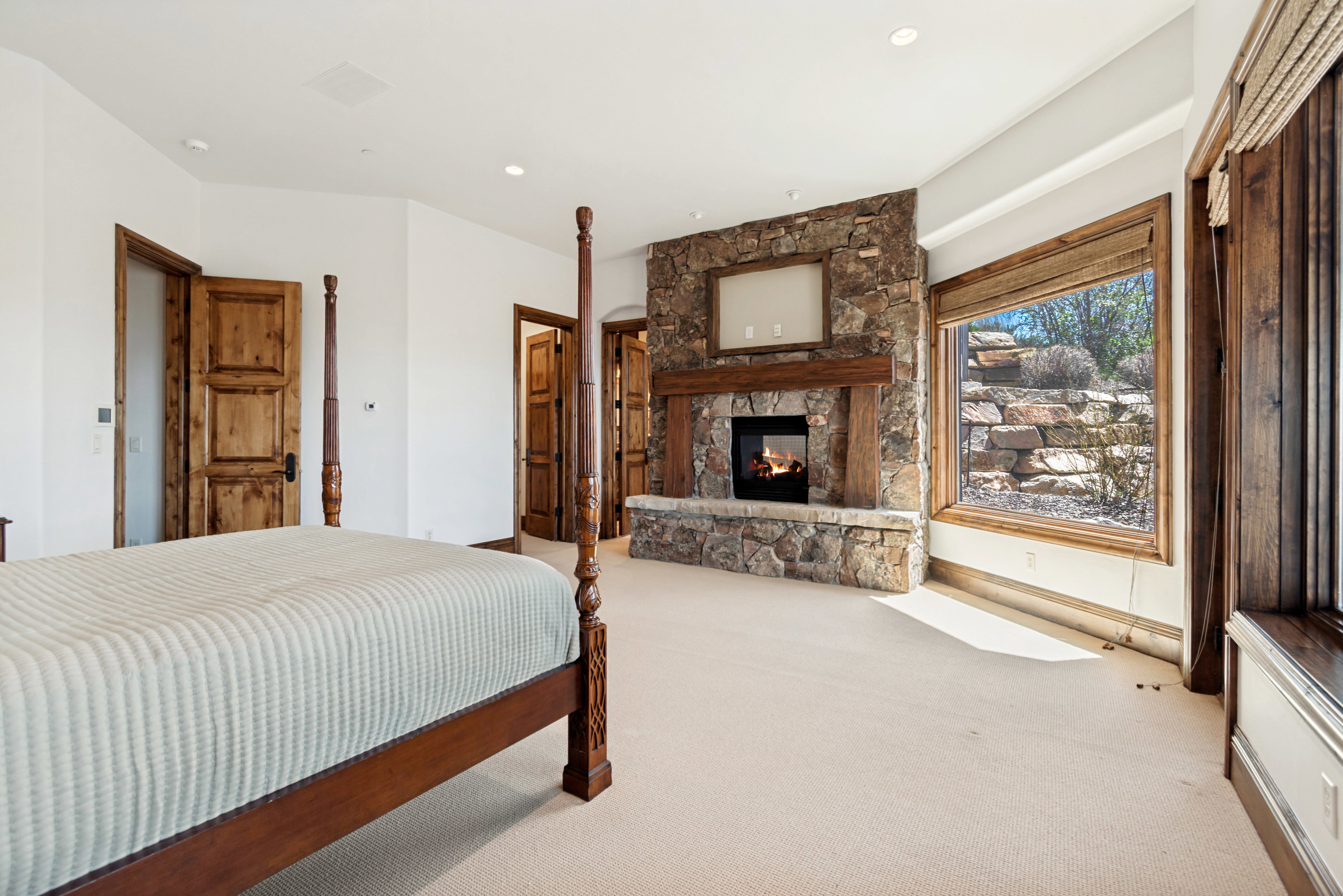 Bedroom featuring a stone-clad fireplace with a natural wood mantel